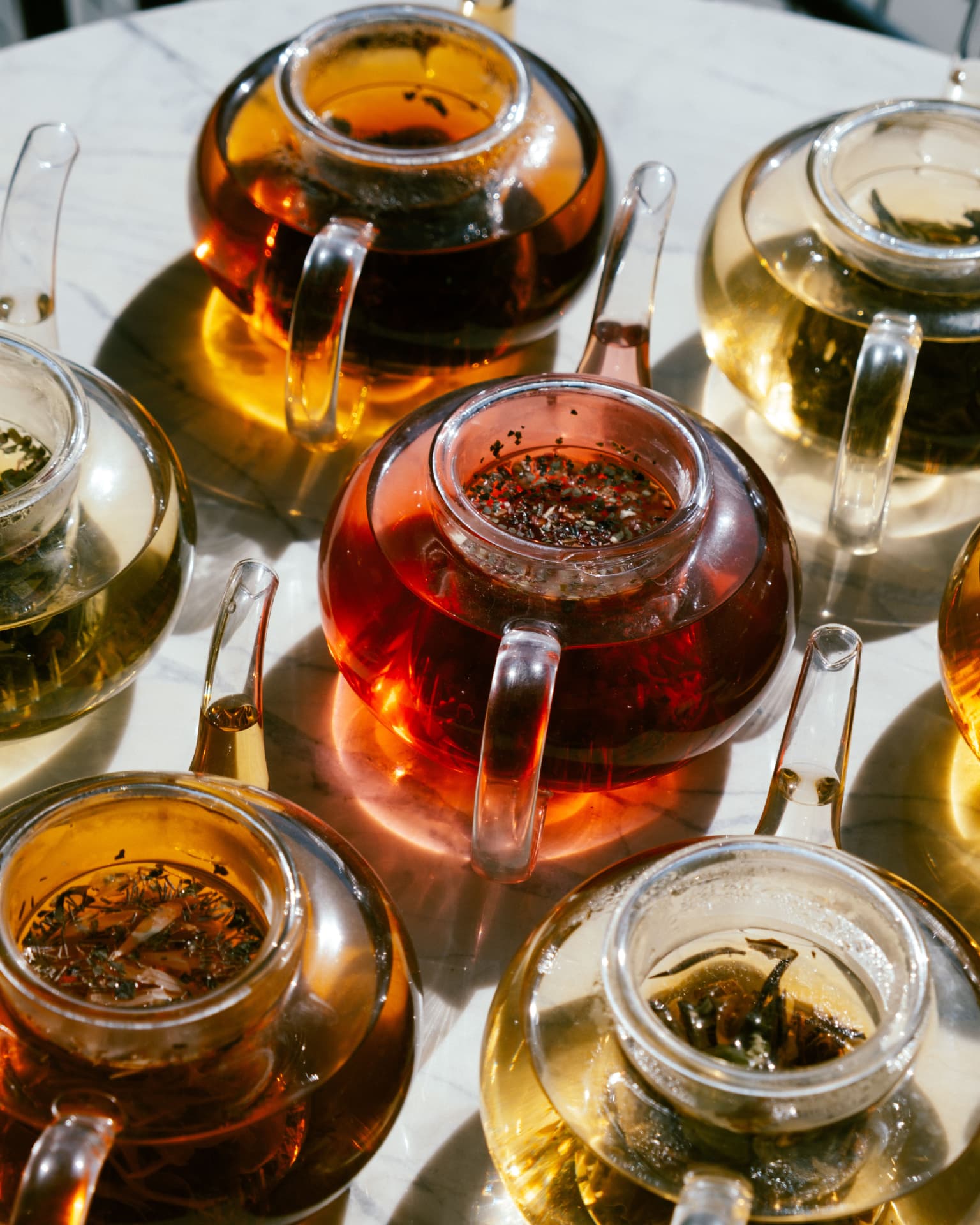 Théières en verre aux couleurs rubis, ambrée et dorée des infusions Sonara Paris